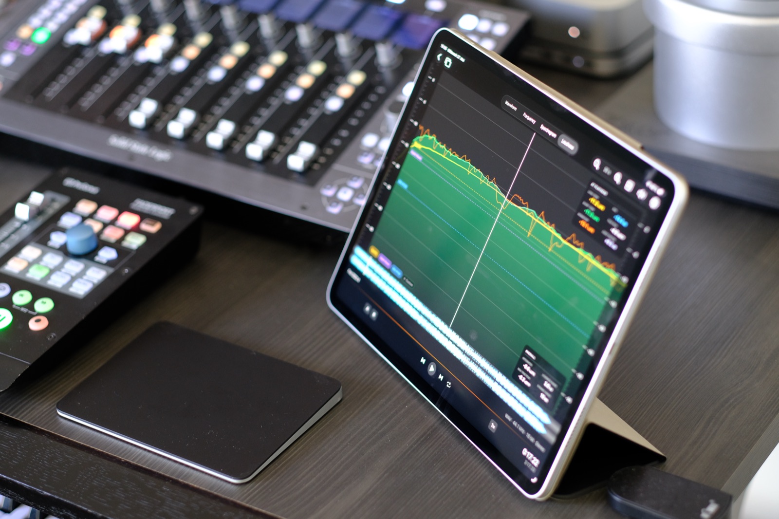 SpectraView Studio on an iPad in a studio setup, with a control surface and trackpad on the desk.